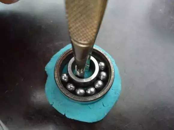 用鑷子或別的相近的物體越過(guò)內(nèi)圈，同時(shí)向滾珠的方向用力頂住